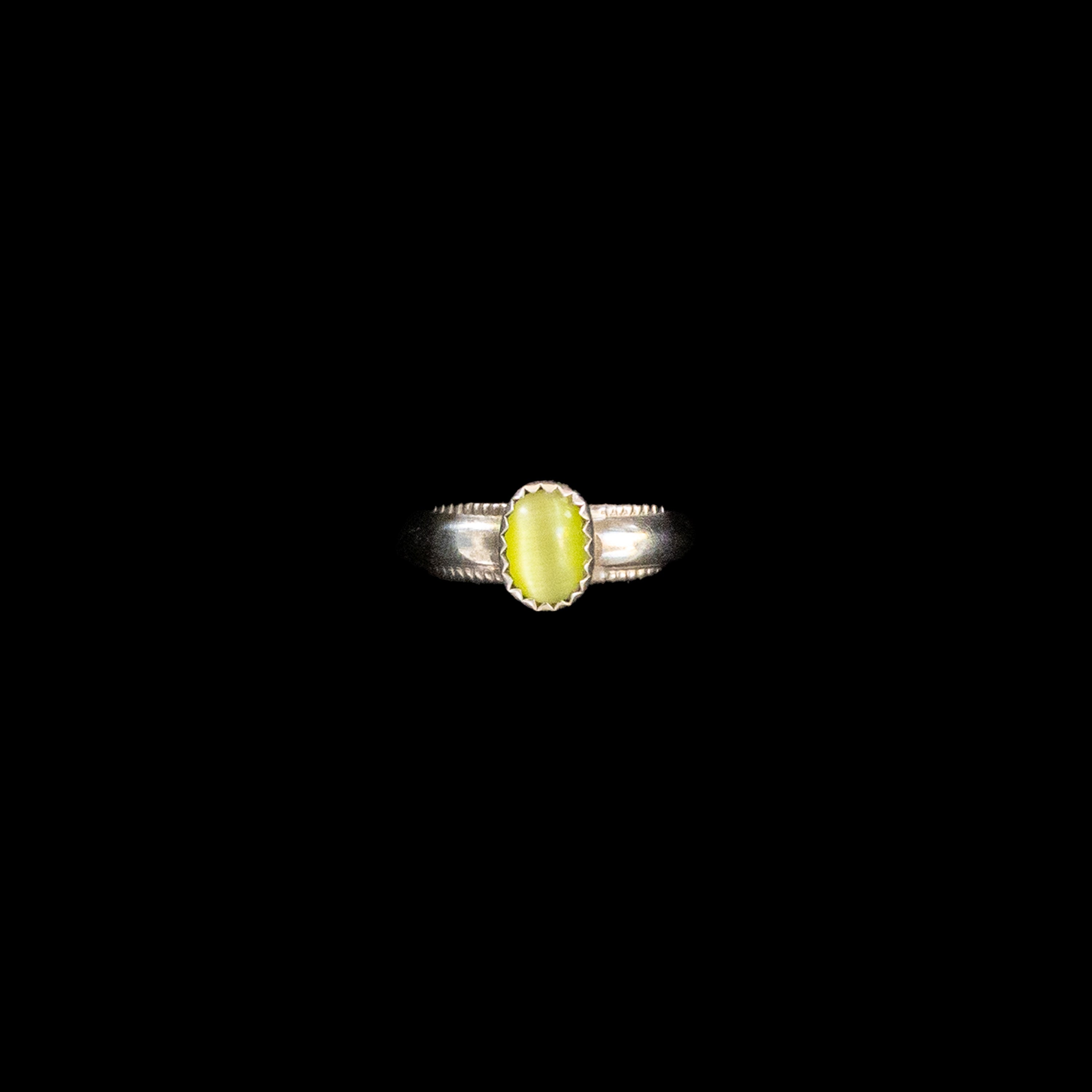 Silver ring with textured band with a glowing yellow stone