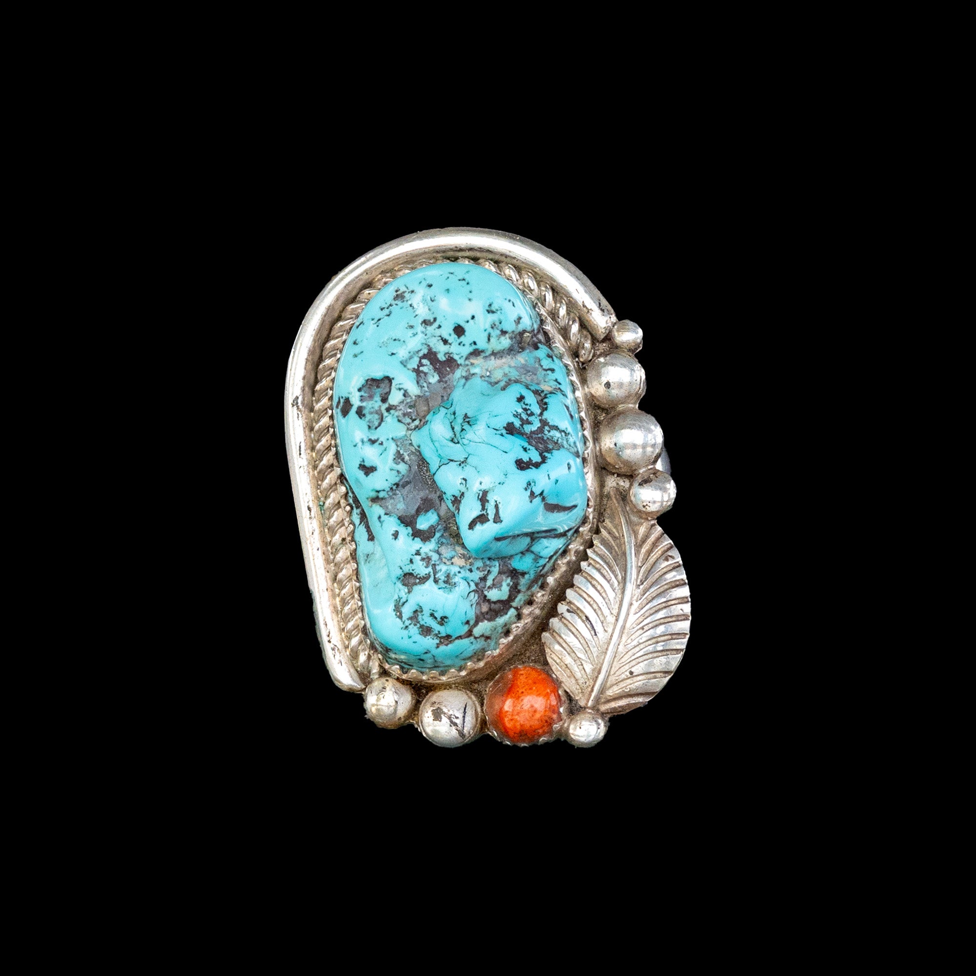 Turquoise stone ring with silver and coral accents on a black background