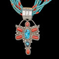 Silver pendant with turquoise and coral stones on a black background