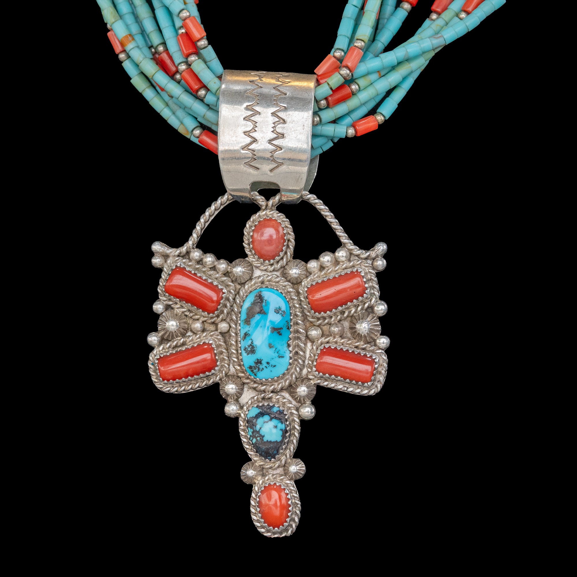 Silver pendant with turquoise and coral stones on a black background