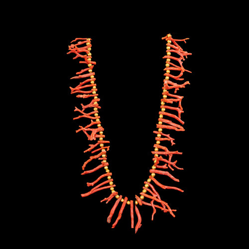 Necklace with coral and gold plated beads on a black background