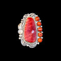 Silver ring with a large red oyster piece and smaller oyster pieces on a black background