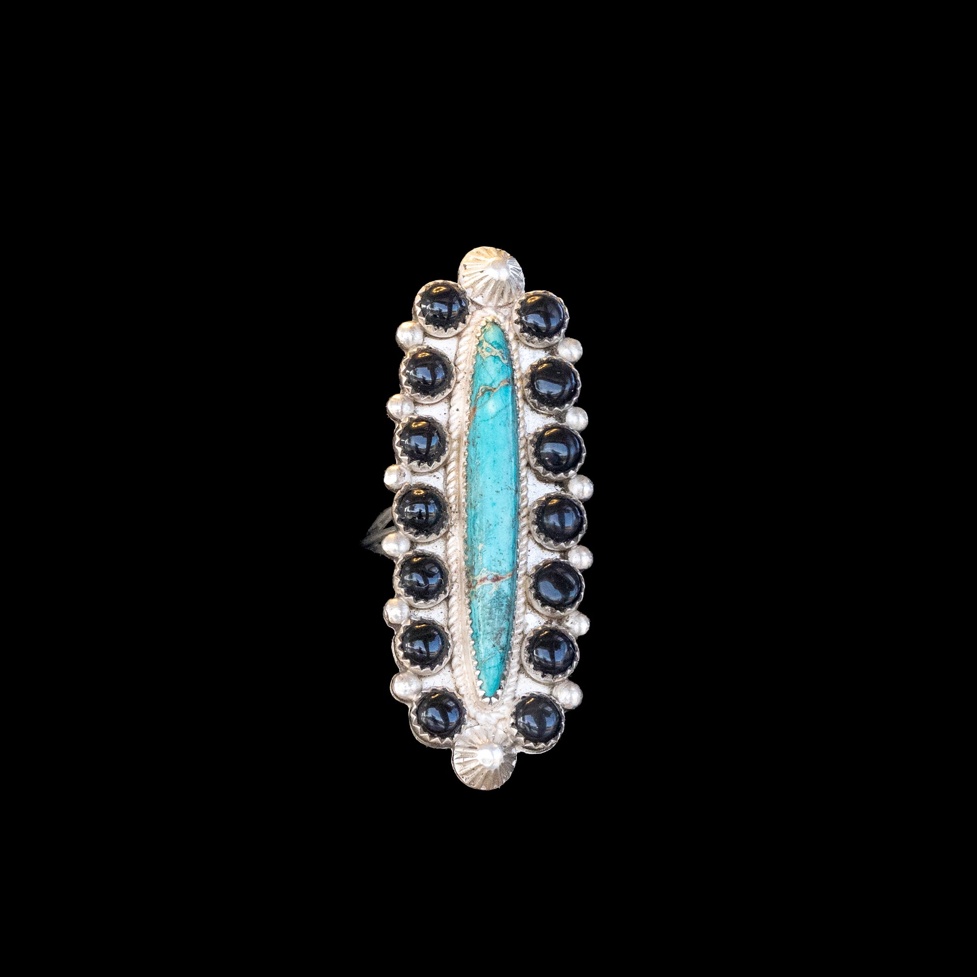 Ring with blue central stone and black stones on a black background