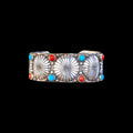 Silver bracelet with sunburst designs and colorful stones on a black background