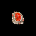 Silver ring with a large piece of coral on a black background