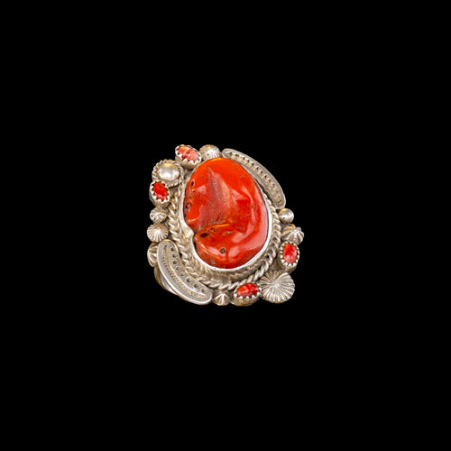 Silver ring with a large piece of coral on a black background