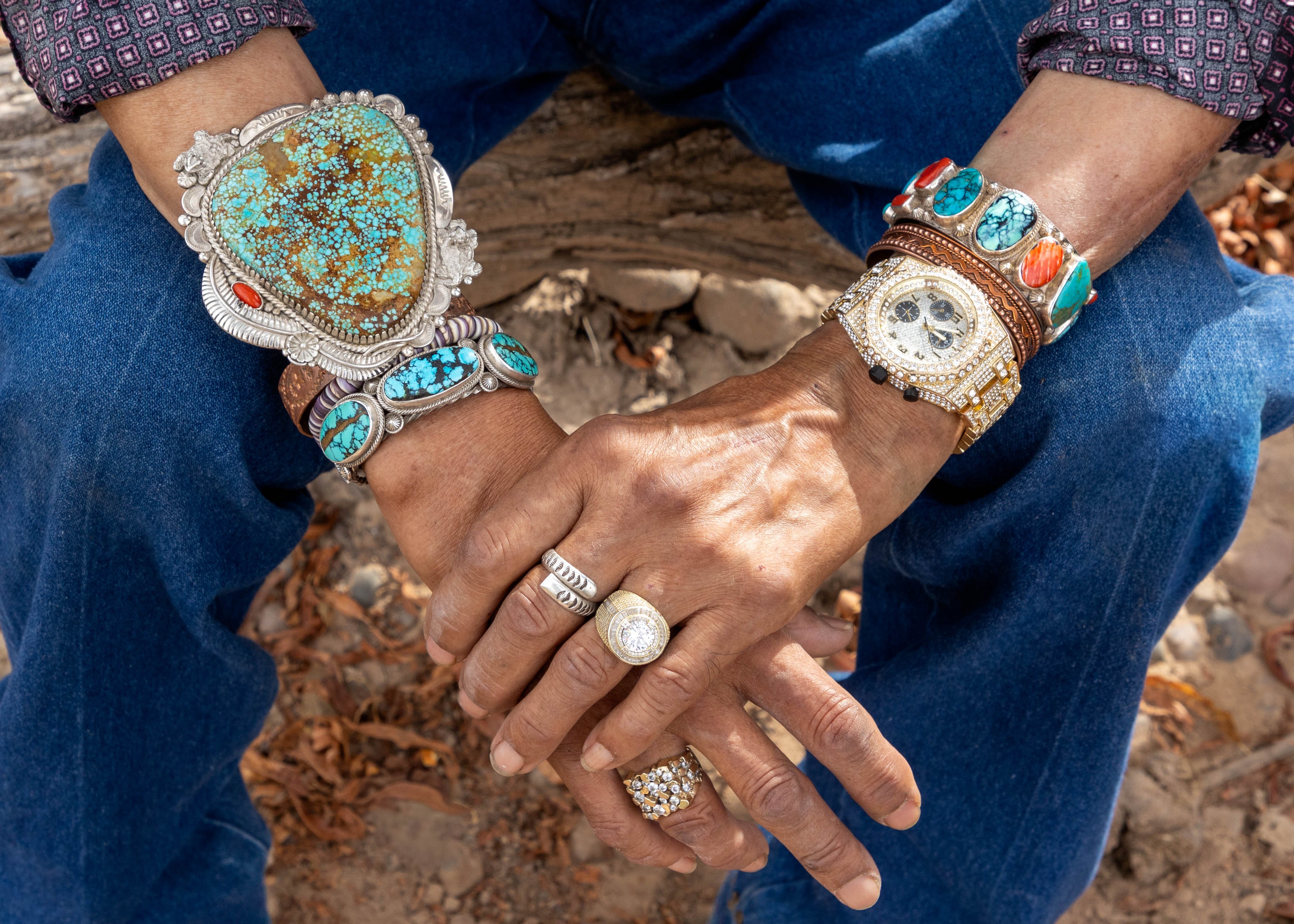 Close-up of hands wearing multiple rings and bracelets with a natural background